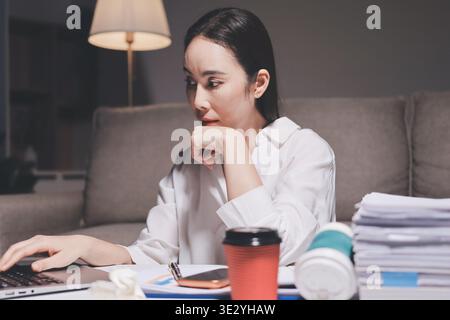 Erschöpfte weibliche Angestellte, die während der Überstunden Burnout erlitten hat. Eine müde Profi-Frau unter Druck mit Kopfschmerzen. Stockfoto