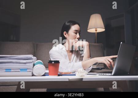 Erschöpfte weibliche Angestellte, die während der Überstunden Burnout erlitten hat. Eine müde Profi-Frau unter Druck mit Kopfschmerzen. Stockfoto