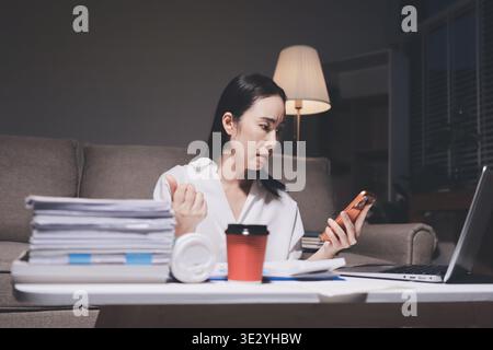 Erschöpfte weibliche Angestellte, die während der Überstunden Burnout erlitten hat. Eine müde Profi-Frau unter Druck mit Kopfschmerzen. Stockfoto
