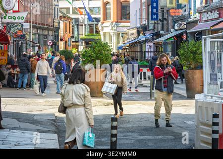 Leute laufen auf der South Anne Street im Stadtzentrum von Dublin mit Geschäften, Restaurants und Restaurants im Freien. Stockfoto