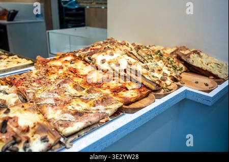 Genua, ligurien, italien. Mai 2024. Verschiedene herzhafte Focaccia- und Pizzastücke, traditionelles ligurisches Street Food zum Verkauf an einem Marktstand i Stockfoto