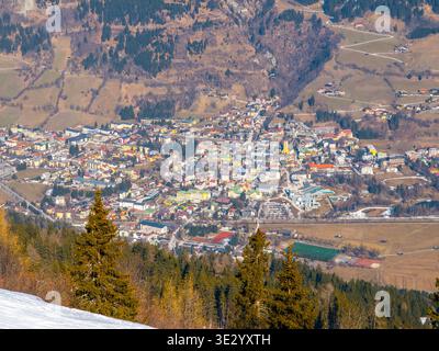 Das Dorf Bad Gastein ist von oben sichtbar. Es ist von Bergen und grünen Feldern umgeben. Diese Ansicht zeigt das Stadtbild mit Gebäuden und Straßen an einem klaren Frühlingstag. Stockfoto