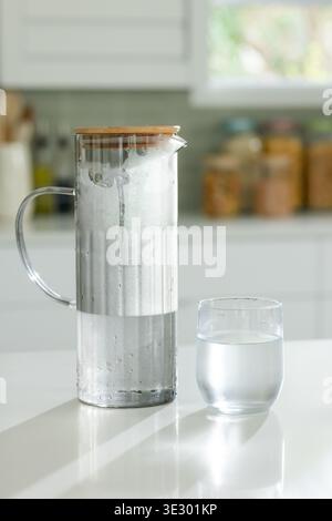Glaskrug mit Holzdeckel, kondensiert und schäumt auf Hochglanz-Küchenarbeitsplatte, Tumbler Stockfoto