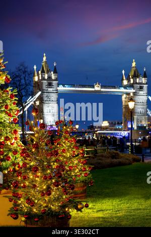 Ein geschmückter Weihnachtsbaum für die Weihnachtszeit vor der Tower Bridge von London, England, während der Abenddämmerung Stockfoto