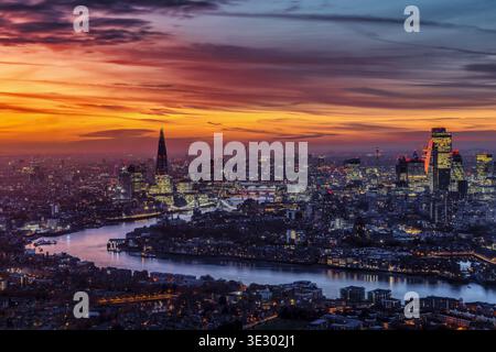 Erhöhter Abendblick auf die beleuchtete Skyline von London nach einem farbenfrohen Sonnenuntergang, England Stockfoto