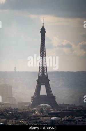 Der Eiffelturm erhebt sich über der Skyline von Paris im weichen, trüben Licht unter dramatischen Wolken. Stockfoto