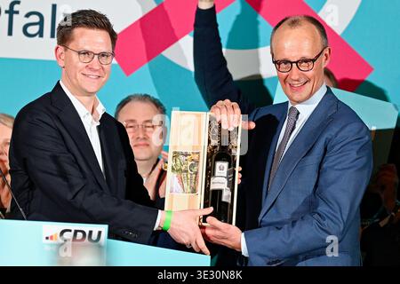 20. März 2026, Rheinland-Pfalz, Bad Dürkheim: Bundeskanzler Friedrich Merz (r, CDU) erhält vom Rheinland-pfälzischen CDU-Generalsekretär Johannes Steiniger in der Salierhalle eine Flasche Wein mit dem Aufdruck „Revoluzzer“. Foto: Uwe Anspach/dpa Stockfoto