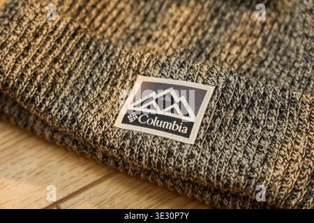 Tyumen, Russland, 11. Dezember 2025: Eine Strickmütze mit einem Logo mit Bergmotiven. Der Hut wird auf eine Holzfläche gestellt Stockfoto