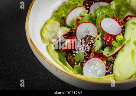Frischer Gemüsesalat aus grünem Salat, Rettich und Gurke mit Dill, grünen Zwiebeln und griechischem Joghurt Stockfoto