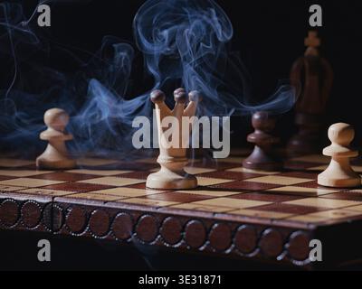 Ein Nahaufnahme-Foto von Rauch, der über einem Schachbrett schwebt, mit einigen Schachfiguren. Stockfoto