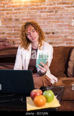 Geschäftsfrau, die von zu Hause aus mit Laptop und Smartphone arbeitet Stockfoto
