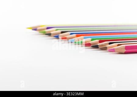 Geschärfte, mehrfarbige Bleistifte, die in einer diagonalen Reihe mit selektivem Fokus auf einem sauberen weißen Hintergrund aufgefächert werden. Stockfoto