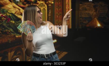 Frau, die australische Banknoten hielt, fächerte in der Hand, während sie den Finger zur Seite im Studio zeigte; Vertrauen Wohlstand. Stockfoto