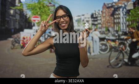 Thailändische Frau hält ein weißes Puzzleteil und blitzt mit der rechten Hand auf eine Straße, die von Fahrrädern und Backsteinhäusern gesäumt ist; Neugier entdeckt. Stockfoto