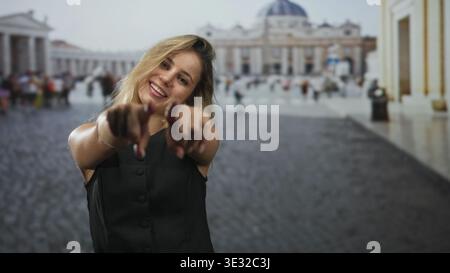 Frau zeigt mit dem Finger auf die Kamera mit beiden Händen im Quadrat auf den vatikan, lächelt und lehnt sich nach vorne; verspieltes Selbstvertrauen. Stockfoto