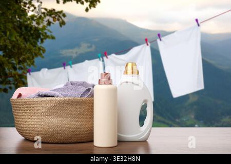 Wäschekorb mit sauberen Handtüchern und Waschmittelflaschen auf dem Tisch gegen Austrocknen der Kleidung Stockfoto