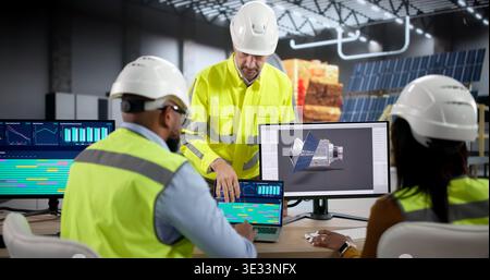 Junge Ingenieure und Wissenschaftler entwerfen Solarpaneele auf Einem Laptop, während sie Teile von Raumfahrzeugen in einem Luft- und Raumfahrtlabor entwerfen Stockfoto