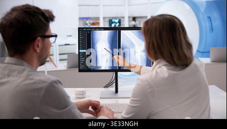 Medizinisches Fachpersonal, das vor der Operation die Knieröntgenuntersuchung auf dem Computerbildschirm analysiert Stockfoto
