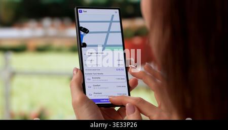 Frau, Die Taxi Über Die Mobile App In Der Stadtumgebung Bucht Stockfoto