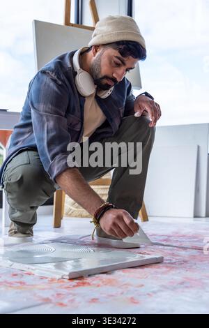 Mit einem Palettenmesser kauert und kratzt Farbe, indischer Künstler arbeitet auf der Leinwand Stockfoto