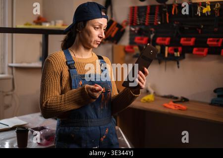 Reparaturfrau, Handwerker oder Mechaniker mit Overalls suchen im Internet mit einem digitalen Tablet in der Garage nach Material, Deals und Rabatt. Kopie sp Stockfoto