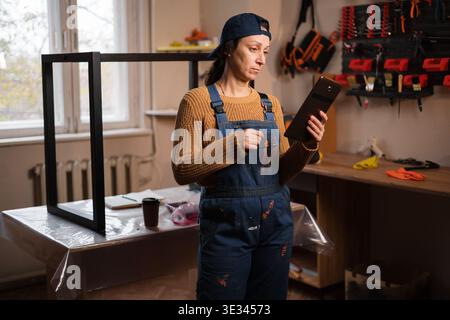 Reparaturfrau, Handwerker oder Mechaniker mit Overalls suchen im Internet mit einem digitalen Tablet in der Garage nach Material, Deals und Rabatt. Kopie sp Stockfoto