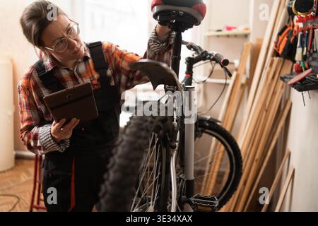 Reparaturfrau erkennt Problem mit ihrem Fahrrad mit einem Tablet-Computer. Kopierbereich Stockfoto