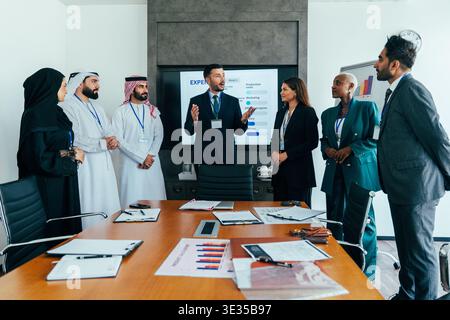 Multiethnische Geschäftsleute, die ein Geschäftstreffen in einem Sitzungssaal des Büros abhalten, ein Referent spricht und gestikuliert, über Strategie und Finanzen diskutiert Stockfoto