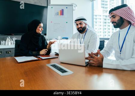 Arabische Geschäftsleute arbeiten zusammen und diskutieren Strategien an einem Konferenztisch mit Laptop und Diagrammen in einem modernen Büroumfeld Stockfoto