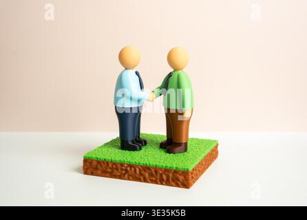 Eine Vereinbarung über den Kauf oder Verkauf eines Grundstücks. Zwei Parteien schließen eine Transaktion ab und unterzeichnen rechtliche Dokumente. Immobiliengeschäft, Eigentumsübertragung und formeller Vertrag zwischen Käufer und Verkäufer. Stockfoto