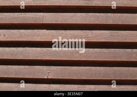 Holzwand aus Gittern. Braune Holzwand. Holzstreifen. Hintergrund Stockfoto