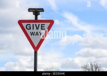 Nahaufnahme eines dreieckigen Straßenschildes in Großbritannien vor einem klaren Himmel, das Verkehrsregeln, Sicherheit und Straßennavigation symbolisiert. Stockfoto