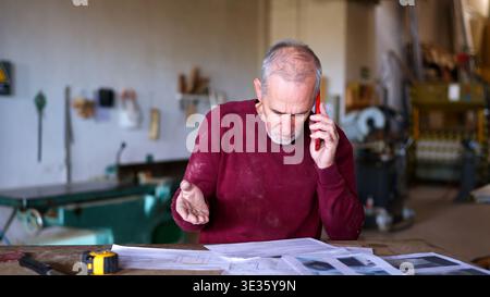 Leitender Handwerker, der einen Anruf entgegennimmt, der Werkstattbetrieb leitet Stockfoto