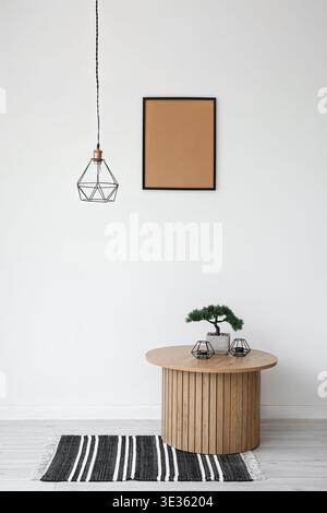 Couchtisch aus Holz mit Bonsaibaum und Kerzenständer in der Nähe der weißen Wand Stockfoto