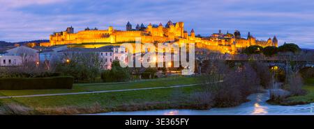 Ein breiter Panoramablick von 65:24 Xpan auf einen Sonnenuntergang über Carcassonne, Frankreich, mit der beleuchteten Cité de Carcassonne, die sich über dem umliegenden Land erhebt Stockfoto