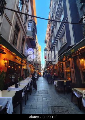 Enge Fußgängerzone in Istanbul, gesäumt von Restaurants und Cafés, mit Esstisch im Freien und lebhafter Atmosphäre.10. märz 2026. Stockfoto