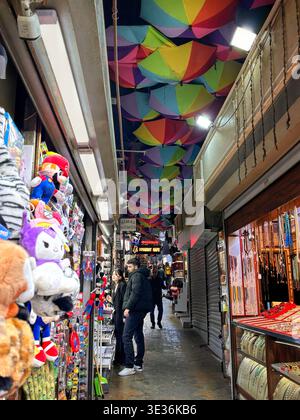 Lebhafte enge Straßenszene in İstiklal – bunte Sonnenschirme, geschäftige Geschäfte, Händler und gemütliche Restaurants schaffen eine lebendige urbane Atmosphäre.10 Marc. Stockfoto