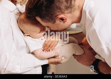 In einem wunderbar zärtlichen Moment umarmen beide Eltern ihr geliebtes Baby herzlich und fangen die tiefgründige und herzzerreißende Essenz von Familienliebe und d ein Stockfoto