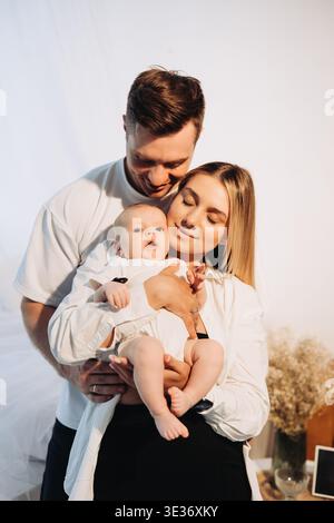 Ein liebevolles Paar teilt einen kostbaren und zärtlichen Moment mit seinem liebenswerten Baby und zeigt die tiefe Verbindung und Freude des Familienlebens in einer Minute Stockfoto