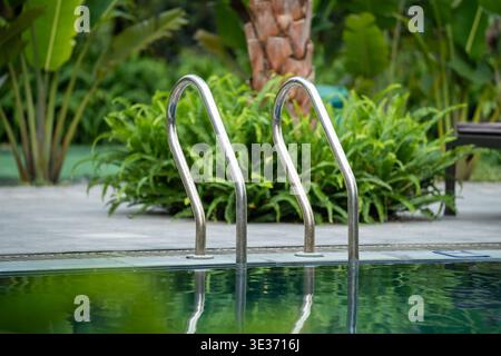 Luxus-Resort-Open-Air-Pool umgeben von Grün und Palmen, komfortabler Bereich zum Ausruhen. Stockfoto