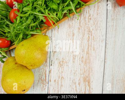Frische Rucola, Kirschtomaten und Birnen auf einem Holztisch Stockfoto