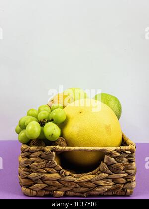 Verschiedene Früchte wie Trauben, Melonen und Birnen in einem gewebten Korb. Züchten Sie frisches Obst und Gemüse in Korb Stockfoto