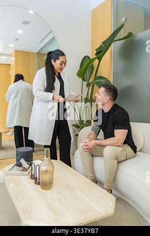 Medizinischer Fachmann diskutiert mit einem männlichen Patienten in einer modernen Dermatologie-Klinik ästhetische und Wellness-Optionen und bietet fachkundige Beratung für den persönlichen Stockfoto