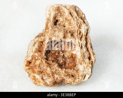 Makroaufnahmen von natürlichen Mineralien - Wulfenit-Kristallen auf rohen Felsen auf weißem Marmor aus dem Uralgebirge Stockfoto