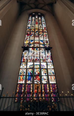 München, Deutschland - 15. April 2025: Hohe Buntglasfenster mit religiösen Szenen in der Frauenkirche in München, Bayern Stockfoto