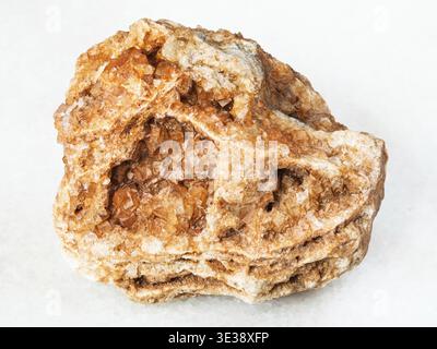 Makroaufnahmen von natürlichem Mineral - Wulfenitkristalle auf rauem Felsen auf weißem Marmor aus dem Ural Stockfoto