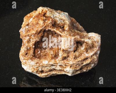 Makroaufnahmen von natürlichen Mineralien - Wulfenitkristalle auf rauem Felsen auf schwarzem Granit aus dem Ural Stockfoto
