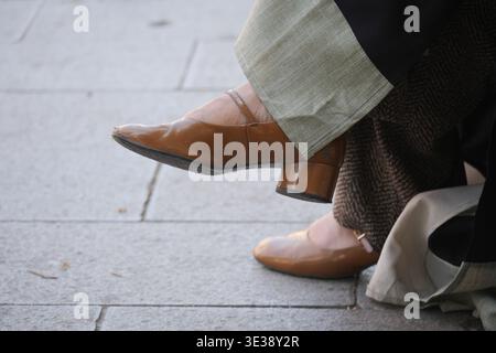 Eine Person mit braunen Absätzen sitzt auf dem Bürgersteig in der Stadt Stockfoto