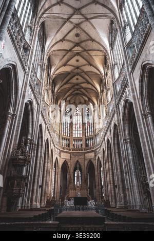 Besucher erkunden das gotische Innere des Veitsdoms auf der Prager Burg. Hohe Bögen und Buntglasfenster schaffen eine historische Atmosphäre an diesem berühmten Ort. Stockfoto