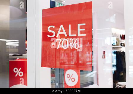Rotes Verkaufsschild mit siebzig Prozent Rabatt im Schaufenster. Saisonales Einzelhandelsangebot im Einkaufszentrum. Verkaufsankündigung für die Räumung. Stockfoto